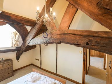 A bedroom with wooden beams a chandelier a chest of drawers and a bed at Above Deck in Beaumaris
