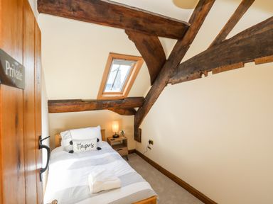 A small bedroom with a single bed a wooden beam ceiling and a skylight window at Above Deck in Beaumaris
