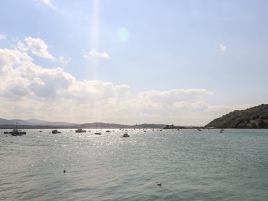 A body of water with boats and hills in the background above deck in beaumaris