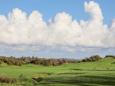 A golf course with a red flag on the green and cloudy sky at Above Deck in Beaumaris