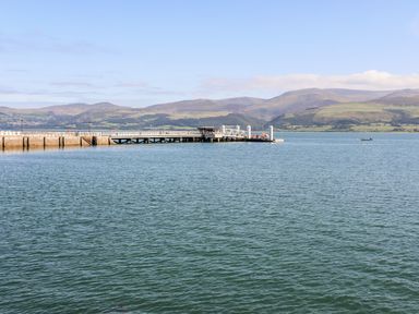 A pier extending into a body of water with hills in the background at Above Deck in Beaumaris