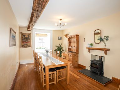 A dining room with a wooden table and six chairs a wood-burning stove and a wooden cabinet at Above Deck in Beaumaris