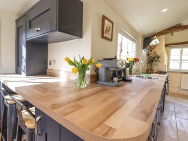 A kitchen with wooden countertop yellow flowers and kitchen appliances at The Abbey Cottage in Windsor Green