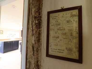 A framed map of Lavenham Suffolk on a wall next to a doorway leading to a kitchen at The Abbey Cottage in Windsor Green