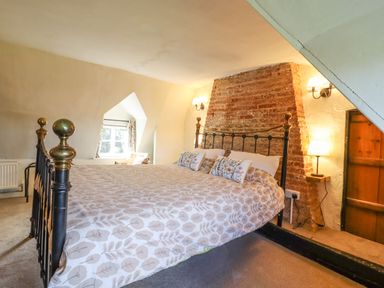 A bedroom with a bed and brick chimney at The Abbey Cottage in Windsor Green