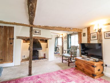 A living room with a fireplace chair television and wooden chest at The Abbey Cottage in Windsor Green