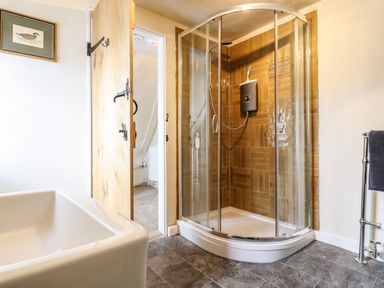 A bathroom with a corner shower enclosure bathtub and wooden door at The Abbey Cottage in Windsor Green