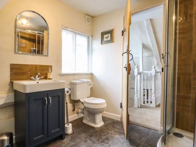 A bathroom with a sink vanity and toilet next to a shower at The Abbey Cottage in Windsor Green
