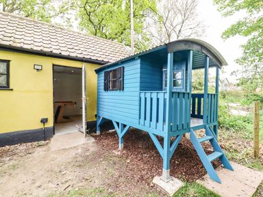 A small blue wooden playhouse with stairs next to a yellow building in a garden at The Abbey Cottage in Windsor Green
