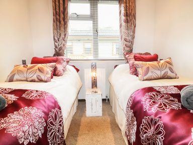 A bedroom with two single beds with pillows and a bedside lamp on a small table at Hafan Lodge 85 Wisemans Bridge near Saundersfoot