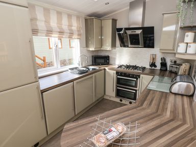 A kitchen with cabinets oven microwave toaster sink and countertop at Hafan Lodge 85 Wisemans Bridge near Saundersfoot