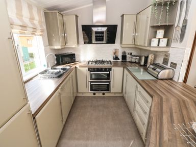 A kitchen with countertops cabinets a stove an oven a microwave a sink and kitchen utensils at Hafan Lodge 85 Wisemans Bridge near Saundersfoot
