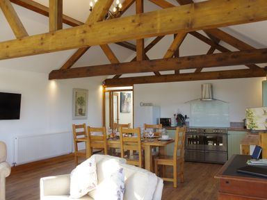 A kitchen and dining area with wooden beams a table with chairs and kitchen appliances at Haimwood Byetake Llandrinio
