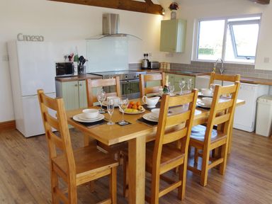 A kitchen with a wooden dining table set with dishes and glasses at Haimwood Byetake in Llandrinio