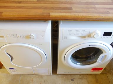 A laundry room with a washing machine and dryer under a wooden countertop at Haimwood Byetake in Llandrinio
