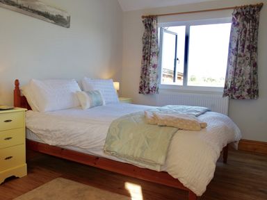 A bedroom with a double bed two yellow bedside tables floral curtains and a window at Haimwood Byetake in Llandrinio