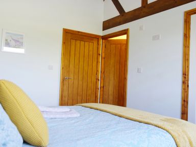 A bedroom with wooden doors a yellow pillow and a light blue bedspread at Haimwood Byetake in Llandrinio
