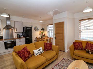 A kitchen and living area with yellow sofas and a dining table at Hardings cottage in Minehead