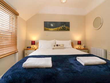 A bedroom with a double bed two bedside tables lamps and folded towels at Hardings cottage in Minehead