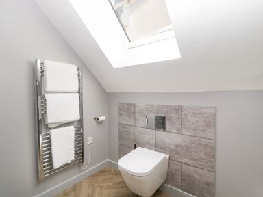 A bathroom with a wall-mounted toilet a towel rack with white towels and a skylight at Little Knaplock in Fiddington near Combwich Somerset