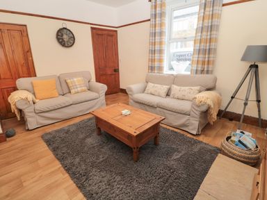 A living room with two sofas a wooden coffee table a floor lamp and a gray rug at Coras House in Amble