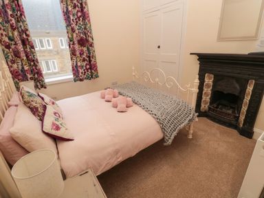 A bedroom with a bed with folded towels and floral curtains at Coras House in Amble