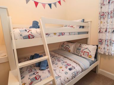 A bunk bed with seaside-themed bedding and blue towels in a bedroom at Coras House in Amble