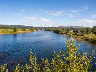 A river flowing through a landscape with trees and hills in the background at Tyn Llwyn Cornel Eco Barn in Garreg