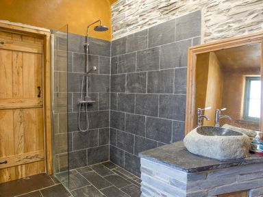 A bathroom with a walk-in shower and stone sink at Tyn Llwyn Cornel Eco Barn in Garreg