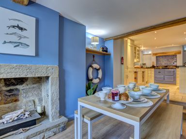 A dining area with a table set for breakfast and a fireplace in a kitchen space at Crab Cottage in Sandsend