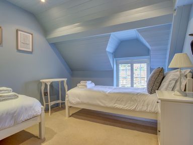 A bedroom with two single beds and a window with shutters at Crab Cottage in Sandsend
