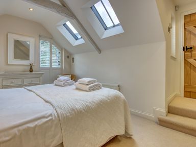 A bedroom with a bed towels on it skylights dresser mirror and a wooden door at Crab Cottage Sandsend
