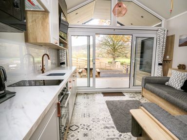 A kitchen and seating area with patterned floor tiles and sliding glass doors opening to a patio at Oak Tree View Nantmel near Rhayader