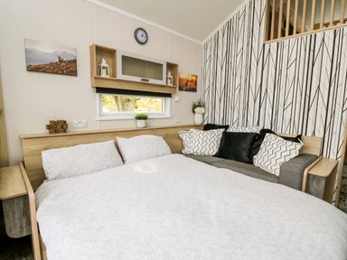A bedroom with a bed a sofa with cushions a small window and wall decorations at Oak Tree View in Nantmel near Rhayader