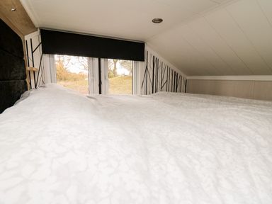 A bedroom with a bed facing windows and patterned wallpaper at Oak Tree View in Nantmel near Rhayader