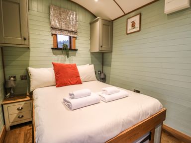 A bedroom with a bed towels bedside tables and a small window at Highland View in Rhayader