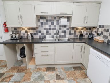 A kitchen with sink toaster kettle dishwasher and cabinets at The Old School in Lowick