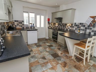 A kitchen with tiled floor cabinets countertop and two chairs at The Old School in Lowick
