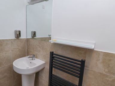 A bathroom sink with a mirror soap dispenser and a black towel rack at The Old School in Lowick