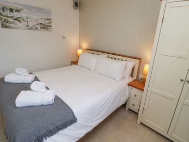 A bedroom with a bed with white linens and towels on a gray throw two bedside tables with lamps and a white wardrobe at The Old School in Lowick