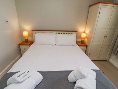 A bedroom with a bed with white linens two bedside tables with lamps and a wardrobe at The Old School in Lowick