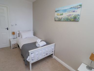A bedroom with a single bed a bedside table with a lamp and a beach painting on the wall at The Old School in Lowick