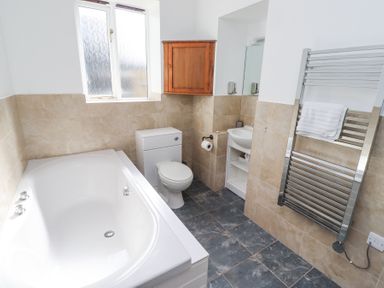 A bathroom with a bathtub toilet sink and towel heater at The Old School in Lowick