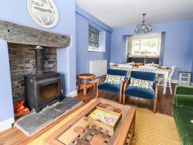 A living room with a wood burner fireplace blue armchairs and dining table at Estcote Roger Ground near Hawkshead