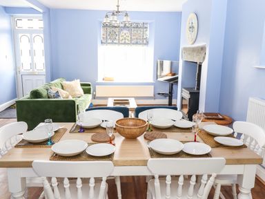 A dining table set with plates and glasses adjacent to a living area with a green sofa and a fireplace at Estcote Roger Ground near Hawkshead