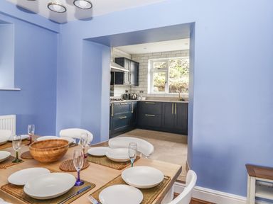 A dining room with a set table and a kitchen with dark cabinets in the background at Estcote Roger Ground near Hawkshead