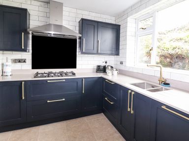A kitchen with dark cabinets a gas stove a stainless steel hood and a window above the sink at Estcote Roger Ground near Hawkshead
