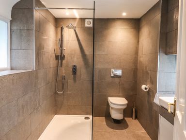 A bathroom with a walk in shower and a wall mounted toilet at Estcote Roger Ground near Hawkshead