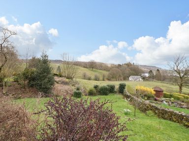 A garden with bushes trees and a wooden shed in a rural landscape at Estcote in Roger Ground near Hawkshead
