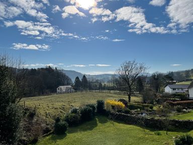 A rural landscape with grassy fields trees hedges and houses at Estcote Roger Ground near Hawkshead